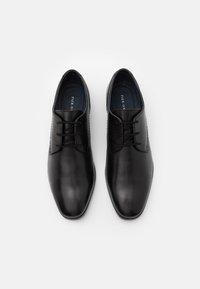 Chaussures habillées en cuir noir avec une finition lisse, un bout pointu, un laçage à l'avant et de discrets accents texturés sur le dessus.