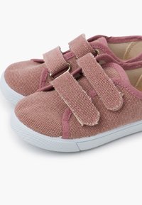 Scarpe da ginnastica rosa in tela con superficie texture, suole in gomma bianche e due cinturini regolabili in velcro sulla parte superiore per una facile calzata.