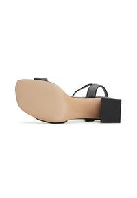 Sandalo nero con tacco a spillo quadrato, sottile fascia alla caviglia e suola liscia beige. Tacco in gomma testurizzata per una migliore aderenza.