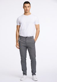 Grijze op maat gemaakte broek met een gladde textuur, voorzien van een knoopsluiting en zijzakken, gecombineerd met een aansluitend wit T-shirt en witte sneakers.