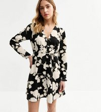 Robe noire enveloppante à manches longues, présentant un motif floral blanc, une taille cintrée et un léger éclat. L'ourlet tombe au-dessus des genoux.