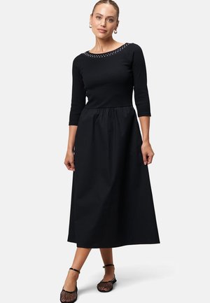 Black dress with three-quarter sleeves, fitted bodice, and a flowing skirt. Features a beaded neckline and a soft, smooth texture.