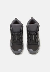 Schwarze und graue High-Top-Schuhe aus Mesh und synthetischem Leder, mit Schnürsenkeln, gepolstertem Kragen und strukturierten Akzenten an den Seiten.