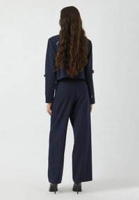 Granatowy garnitur w paski z krótką marynarką i szerokimi spodniami, z delikatnymi zdobieniami, gładką teksturą i dopasowanym krojem.