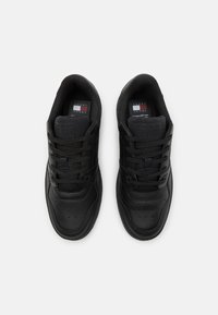 Scarpe sportive nere con esterno in pelle liscia, linguetta in mesh testurizzato, punta rotonda e lacci neri piatti. Dettagli perforati sulla parte anteriore della scarpa.