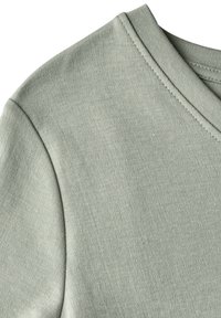 Tričko s krátkým rukávem a výstřihem do V vyrobené z měkké, světle zelené látky s hladkou texturou a jemným švem podél výstřihu.