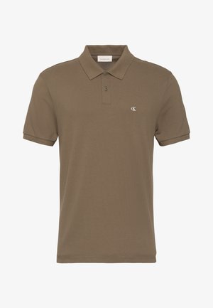 Hnedá polokošeľa s krátkym rukávom, dvoma gombíkmi a malým bielym logom "cK" na ľavej strane hrude.