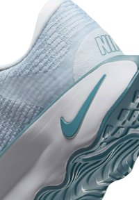 Sapatilha Nike com um tecido superior azul claro, entressola branca, destaques em turquesa e uma sola texturizada com padrões ondulados.