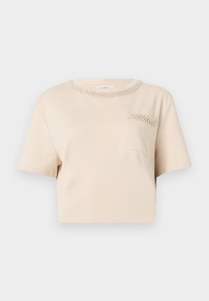 Bežs īsām piedurknēm T-krekls ar apaļu kakla izgriezumu, kas rotāts ar pērlīšu detaļām un mazu krūšu kabatu ar līdzīgu pērlīšu dizainu.