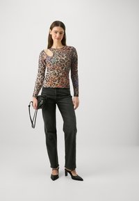 Majica dugih rukava s leopard uzorkom i izrezom, u kombinaciji s crnim trapericama visokog struka i crnim cipelama na petu. Jednostavna crna torba.