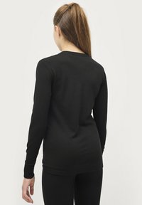 Zwarte langemouwen top, ronde hals, gemaakt van een zachte, lichte stof. Fitted ontwerp, minimale naden, met ribbels aan de manchetten.
