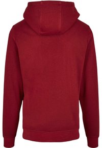 Röd hoodie i ett mjukt, texturerat tyg. Har en rymlig huva, långa ärmar och ribbat fåll och manschetter. Inga synliga logotyper eller grafik.