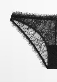 Black lace thong featuring floral patterns, intricate edges, and a smooth fabric panel. Delicate texture with see-through elements.