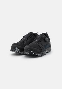 Black athletic shoes with a textured upper, mesh accents, BOA lacing system, and a rugged sole featuring a black and white patterned tread.