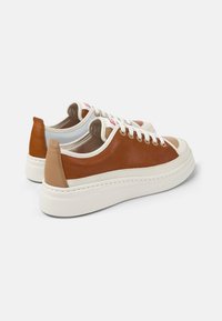 Bruna lädersneakers med krämfärgade detaljer, rund tå, vit sula och perforerade detaljer på hälen. Snören och logotyp på tungan.
