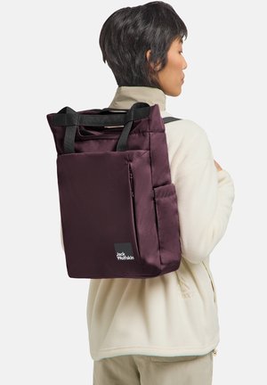 Maroon backpack with two black handles, zip closure, side pocket, and branded tag. Made from smooth fabric; rectangular shape.