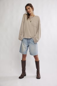 Bēša vafeles raksta garām piedurknēm topiņš ar kabatu, kopā ar gaismzilām džinsa šortiem un brūnām ceļgalu augstām zābakām. Vienkāršs, ikdienišķs dizains.