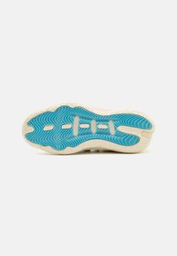 Zool van een sneaker met een gestructureerd blauwe rubberen oppervlakte met witte accenten en een golvend patroon. Licht crèmekleurige randen.