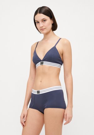 Marineblå bh med V-formet front, tynne stropper og en stripete elastisk bånd. Kombinert med matchende marineblå boyshorts med lignende midjebånddesign.