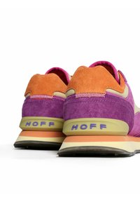 Zapatillas de ante púrpuras y naranjas con una entresuela beige y detalles texturizados, que presentan un logo en el talón y acentos en contraste.