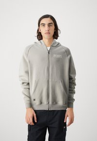 Siva zip-up hoodie iz mehkega materiala, z logotipom "PEOUS" spredaj, dvema sprednjima žepoma in rebrastimi manšetami na robu in rokavih.