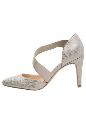 Chaussure à talon haut argentée texturée avec bout pointu et large bride élastique traversant le dessus.