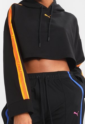 Sort kort Puma-hættetrøje med orange sidelister og matchende sorte træningsbukser med blå og pink Puma-logo accenter.