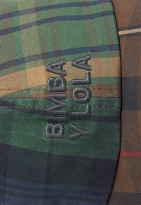 Tkanina w kratę w kolorze zielonym, brązowym i granatowym o gładkiej fakturze; z haftowanym logo "BIMBA Y LOLA" w ciemnoszarym kolorze na pierwszym planie.