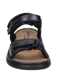 Sandalo in pelle nera con due cinturini regolabili in Velcro, punta arrotondata e soletta imbottita marrone. Suola nera cucita per maggiore durata.