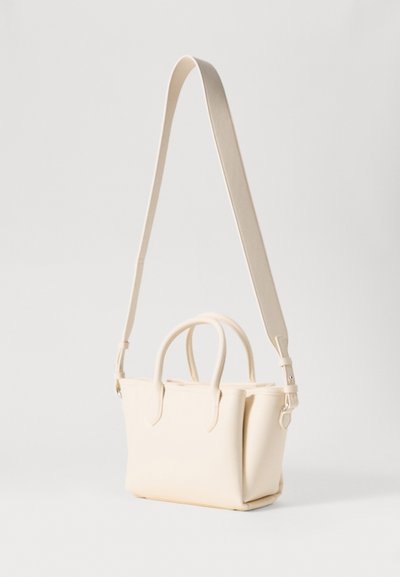 Bolso de mano color crema con un diseño estructurado, dos asas cortas y una correa para el hombro ajustable y desmontable. Textura suave con un hardware mínimo.