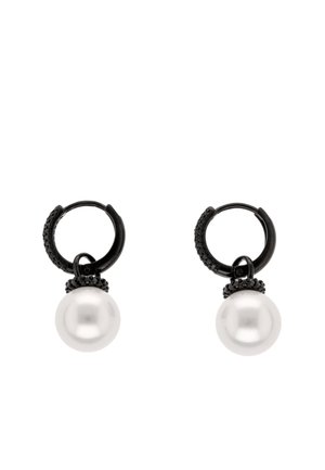 Para czarnych kolczyków kołowych z małymi czarnymi kamieniami i dużymi białymi perłowymi zawieszkami wiszącymi na każdym kolczyku.