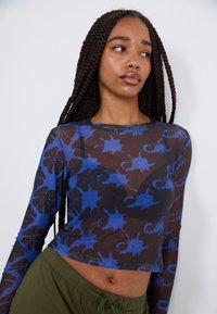 Prozoren top z dolgimi rokavi z črnim ozadjem, ki vsebuje modre cvetlične in škorpijonske vzorce ter kvadratno skrajšano obliko.