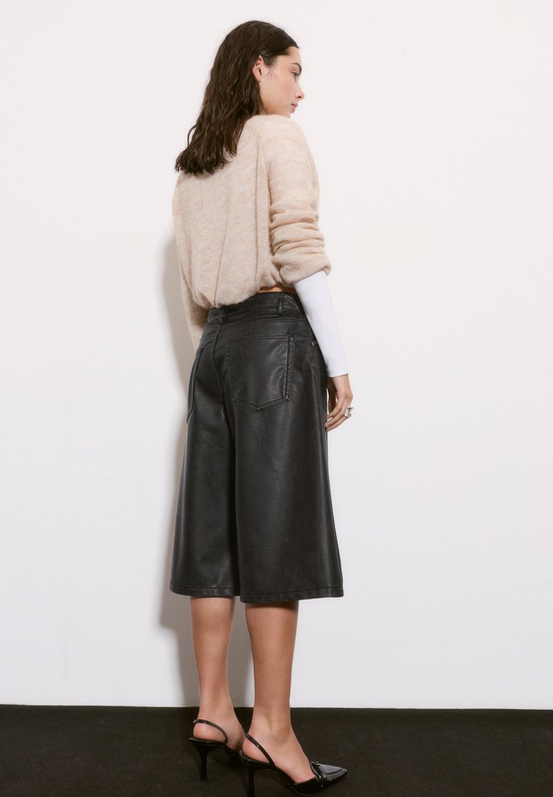 Čierne kožené culottes majú uvoľnený strih, dĺžku po polovicu lýtok a zadné vrecká. Vhodne skombinované s béžovým chlpatým svetríkom a čiernymi lodičkami.