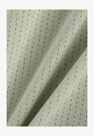 Hellgrüner Stoff mit gleichmäßig verteilten kleinen Perforationen und sichtbarer Strickstruktur, gezeigt in sanften Falten.