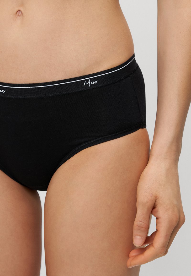 Schwarze Baumwollunterhose mit einem elastischen Bund in Weißstreifen, auf dem der Markenname "Mexx" in geschwungener Schrift steht. Glatte Textur, klassisches Panty-Design.
