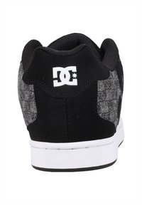 Schwarze und graue Sneakers mit einem strukturierten Stoff-Obermaterial, glattem schwarzen Fersenbereich, weißem Logo und einer weißen Gummisohle mit einem gemusterten Profil.