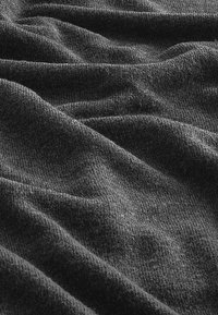 Tissu gris foncé avec une surface douce et texturée, présentant de douces plis et rides, indicatives d'un matériau tricoté.