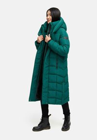 Cappotto imbottito lungo color teal con cappuccio, caratterizzato da una trama trapuntata, una zip frontale, due tasche laterali con zip e un patch con il marchio sulla manica.
