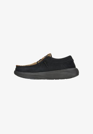 Scarpa nera in camoscio con un accento in pelle marrone testurizzata sulla punta. Presenta una punta rotonda, dettagli con lacci e una suola in gomma per una buona aderenza.