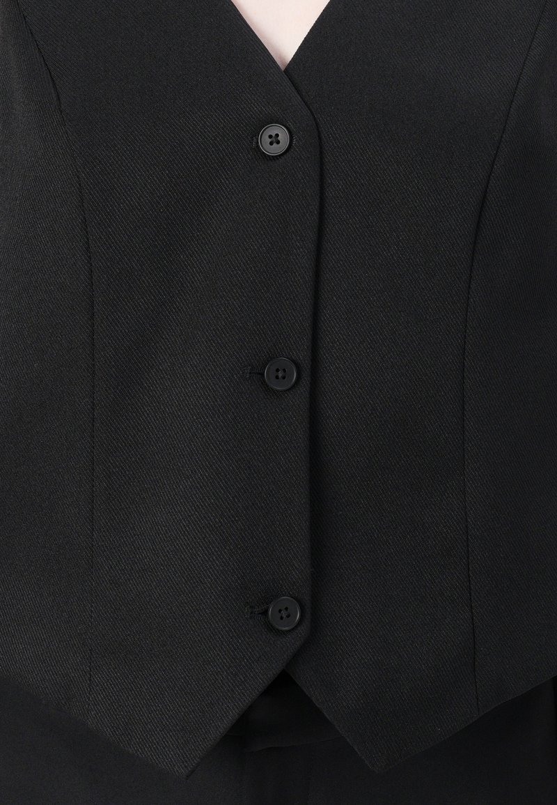 Gilet noir ajusté avec un décolleté en V, comportant cinq boutons sur le devant, et un tissu texturé. Surface lisse avec une coupe cintrée.