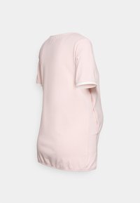 T-shirt de algodão rosa com mangas curtas e acabamento branco à volta do colarinho e das mangas. Barra arredondada e fendas laterais para maior flexibilidade.