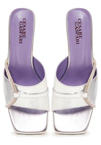 Sandales à talons hauts métalliques argentées avec un bout carré, dotées d'une semelle intérieure violette et d'une sangle perlée au milieu.