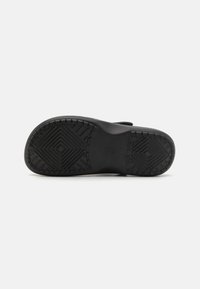 Semelle de chaussure en caoutchouc noir présentant une surface texturée avec des motifs géométriques et un relief prononcé pour une adhérence et une durabilité accrues.
