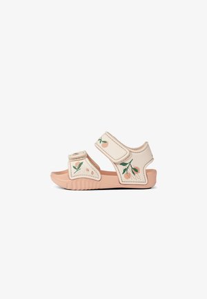 Beige sandals with floral embroidery and velcro straps. The sole is light peach, featuring a textured grip for traction.