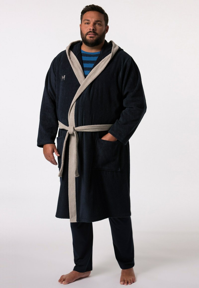 Marinblå frottébadrock med en ljusgrå huva och bälte, med två framfickor, bärs över en randig blå skjorta och mörka byxor.