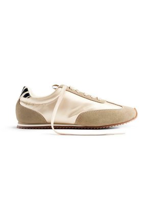 Chaussure de sport beige avec un mélange de satin et de suède, design à lacets, bout rond et semelle en caoutchouc texturée. Accent de talon rayé.