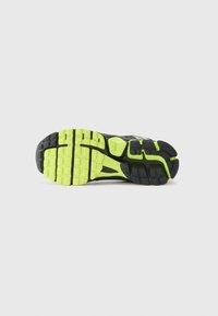 Semelle de chaussure de sport noire avec une texture antidérapante, mettant en avant un accent jaune-vert vif et des motifs de semelle distincts pour une meilleure traction.