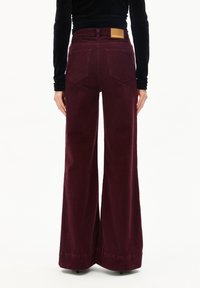 Bordeaux wijde jeans hebben een hoge taille, grote achterzakken en een nep leren patch op de achterkant van de tailleband. Gemaakt van denimstof.