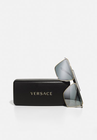 Ochelari de soare Versace cu lentile gri, design geometric, accente aurii și brațe din metal texturat. Include o husă din piele neagră embosată cu "Versace."