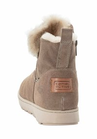 Beige suède enkellaars met witte fleece voering, voorzien van een ritsluiting en een leren patch met het "camel active" logo op de hiel.